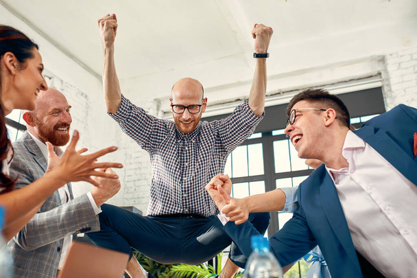 Aufgeregte Mitarbeiter unterschiedlicher Unternehmensteams, die schreiend gute Nachrichten feiern, gewinnen Unternehmenserfolg, fröhliche multiethnische Kollegen, Arbeitsgruppe, die sich über große Leistung begeistert zeigt - Foto, Bild