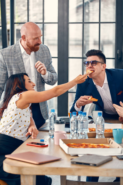 Equipo de negocios feliz comiendo pizza en la oficina.Concepto de negocios, comida, almuerzo y gente. - Foto, imagen