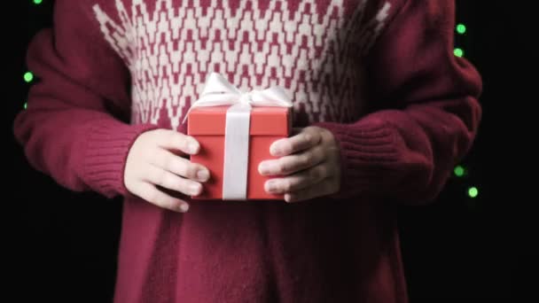 childs manos dando caja roja con cinta blanca. navidad, concepto de año nuevo - Imágenes, Vídeo