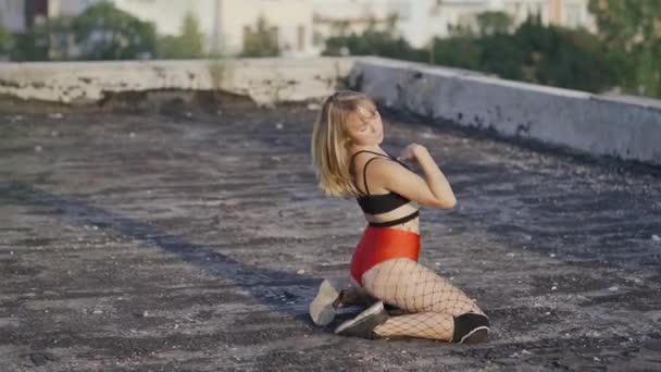 Dziewczyna tańczy twerk na dachu opuszczonego budynku. Dziewczyna w czerwonych spodenkach i rajstopach w celi. - Materiał filmowy, wideo