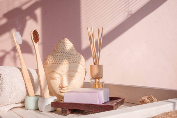 Valkoinen Buddha rintakuva pastelli vaaleanpunainen tausta koristeltu sävyjä. Nolla jätettä bambu hammasharja. Aasialaiseen tyyliin. Rentoudu Joogatausta. Ympäristöystävällinen. Laadukas kuva - Valokuva, kuva