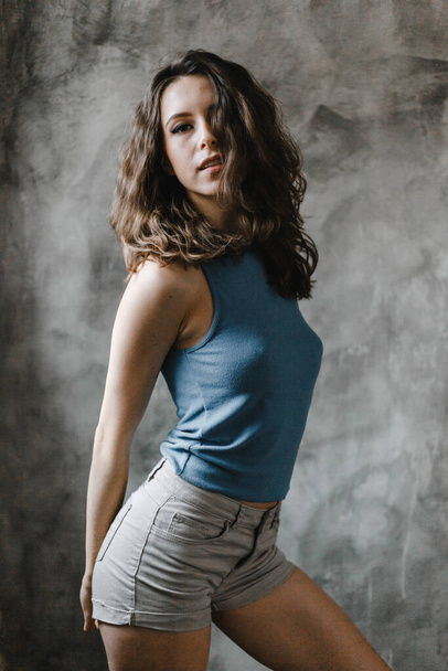 Beautiful cute curly girl posing in shorts and blue t-shirt - Zdjęcie, obraz