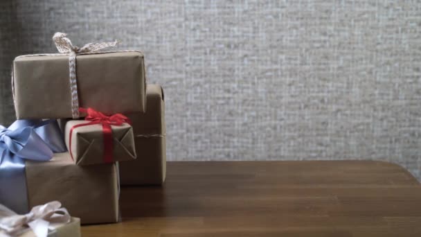 brings three cardboard boxes to the table. Many wrapped gifts lie - Footage, Video