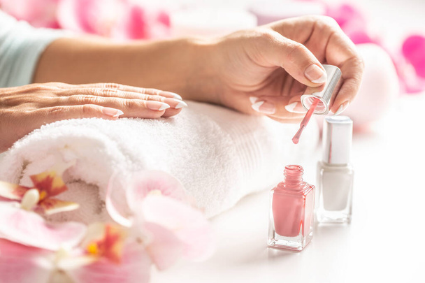 Light pink nail polish applied on a hand of a woman. - Fotó, kép