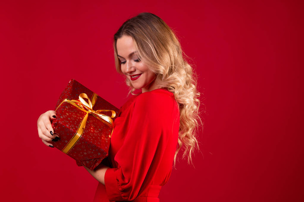 Get a gift, a happy young woman in a red dress got a nice surprise for new year, Christmas or birthday. - Photo, image