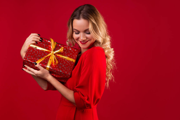 Get a gift, a happy young woman in a red dress got a nice surprise for new year, Christmas or birthday. - Fotó, kép