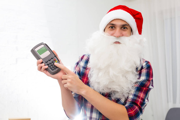 Portrait von seinem schönen attraktiven Weihnachtsmann, der das digitale Terminal-System des Handels in der Hand hält - Foto, Bild