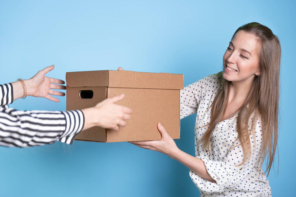 Você envia, transfere e aceita uma caixa com um pacote de mão em mão, uma jovem recebe um presente ou entrega. - Foto, Imagem