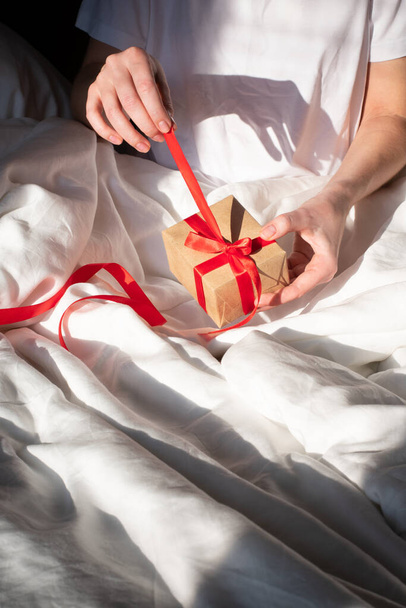 Young girl unpacks a christmas gift in bed - Foto, imagen