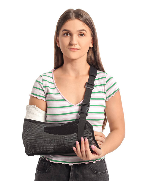 Mujer joven con el brazo roto sobre fondo blanco - Foto, Imagen