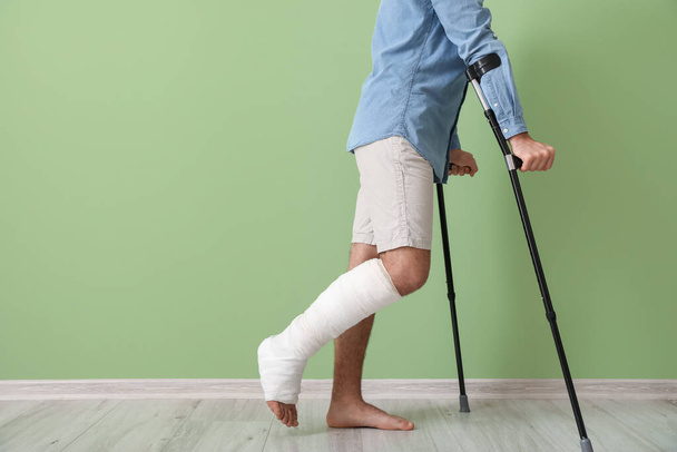 Young man with broken leg near color wall - Fotó, kép