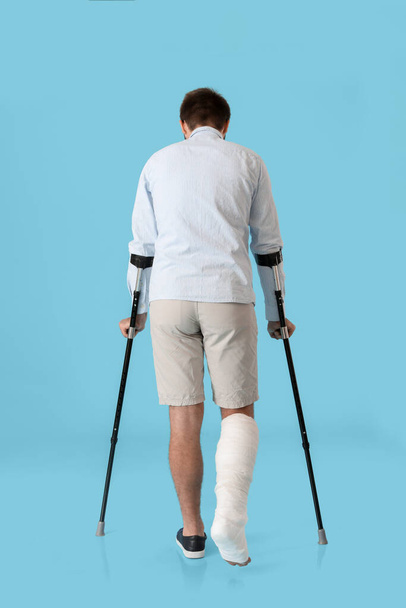 Young man with broken leg on color background - Fotó, kép