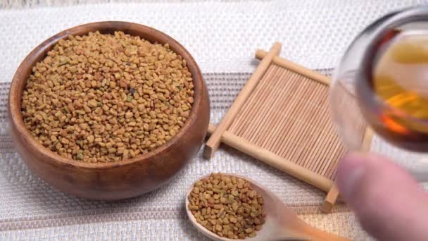 Bebida curativa, semillas, fenogreco de plantas medicinales en un primer plano de mesa ligera de madera. granos de shambala para uso en medicina alternativa - Metraje, vídeo