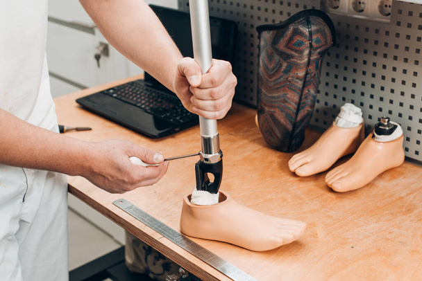 Technician checking artificial limb while at desk in workshop, adjusting it and checking for quality. the latest prosthetic technologies - Photo, Image