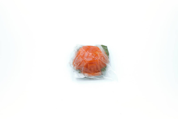 Oválný tvar čínské pečivo červená želva dort zabalený v plastu přes bílé pozadí - Fotografie, Obrázek