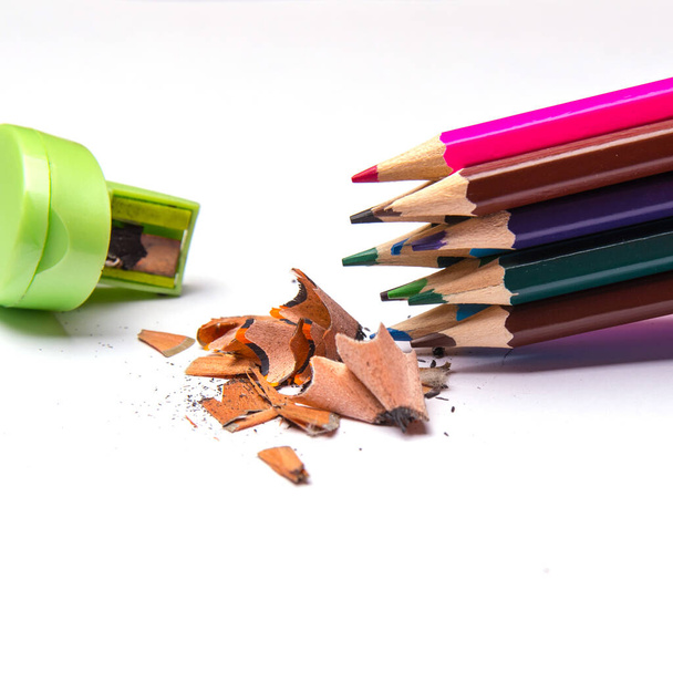 Lápis coloridos e afiador de metal, arquivamentos a lápis coloridos isolados em um fundo branco, close-up, espaço para texto - Foto, Imagem
