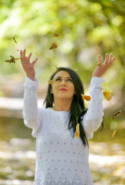 Happy woman and autumn leaves in the park. - Photo, Image