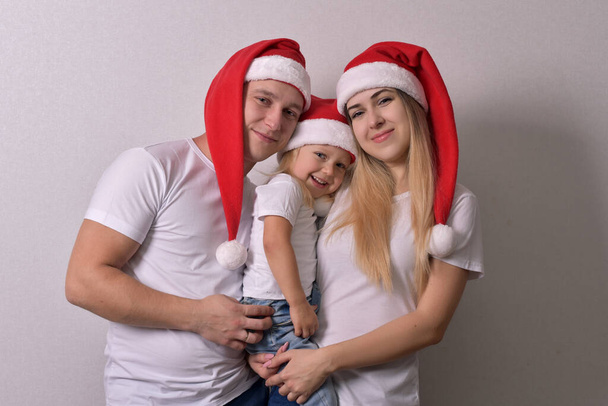 Young parents and child in Santa hats on white background - Foto, immagini