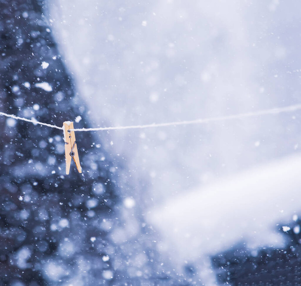 Kleurrijke wasknijper op het touw in de sneeuwstorm buiten - Foto, afbeelding