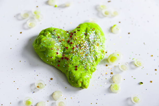 Zielone serce z błyszczącymi brokatami wykonane ze szlamu po dziecku - Zdjęcie, obraz