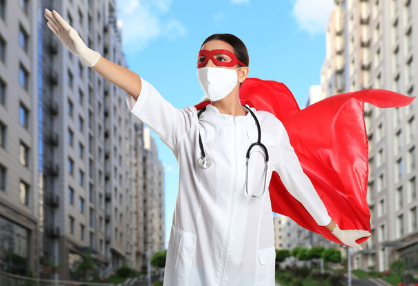 Doctor dressed as superhero on city background. Medical workers fighting with dangerous diseases - Foto, Bild