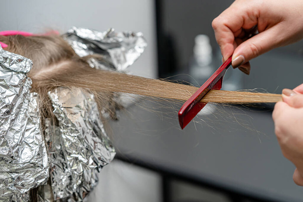 Friseur macht Bouffant mit Kamm auf dünnen Strängen. Shatush-Technik zur Haaraufhellung - Foto, Bild