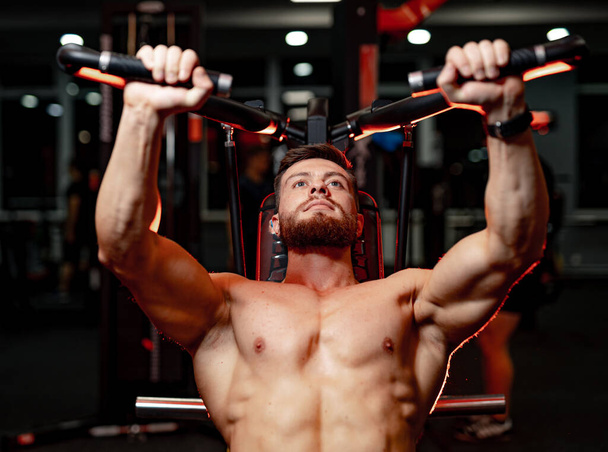 Fit young man lifting weights doing workout at a gym. Sport, fitness, weightlifting, bodybuilding, training, athlete, workout exercises concept. Front view. - Foto, imagen