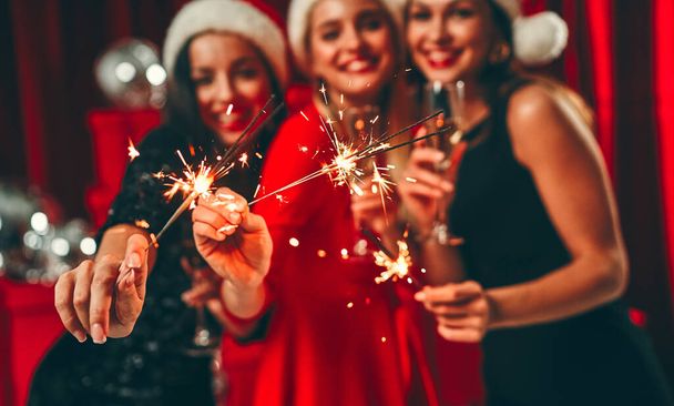 Homályos kép három gyönyörű, szexi nő Mikulás sapkában, egy pohár pezsgővel és csillogással. Újévi buli. Szenteste. - Fotó, kép