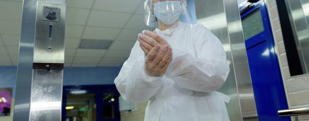 Doktor v ochranném obleku si utírá ruce v nemocnici.. - Fotografie, Obrázek