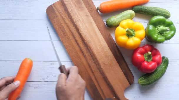 vista superior de mans mano corte zanahorias frescas sobre tabla de cortar en la mesa  - Imágenes, Vídeo