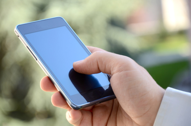 egy üzletember leosztás holding, és használ egy okos telefon szabadban közelről - Fotó, kép