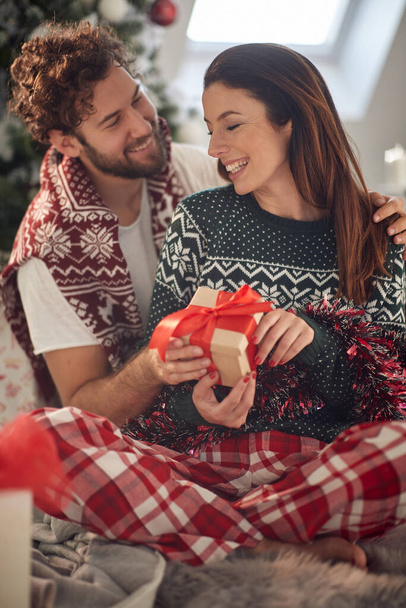 A young couple in love spending a Christmas morning at home sharing presents in a relaxed atmosphere. Christmas, relationship, love, together - Fotó, kép