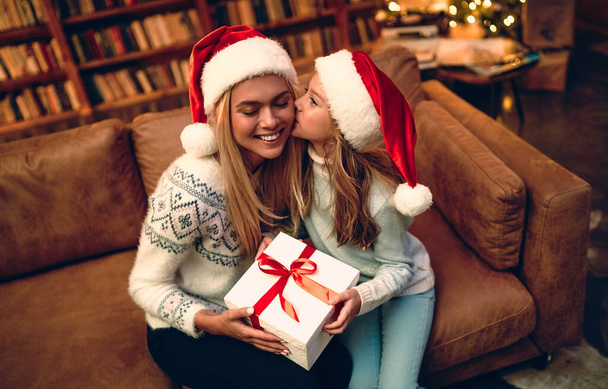 Joyeux Noël et Joyeuses Fêtes ! Joyeux maman et sa fille mignonne fille échanger des cadeaux. Parent et petit enfant s'amusent près de l'arbre à l'intérieur. Famille aimante avec des cadeaux dans la chambre. - Photo, image