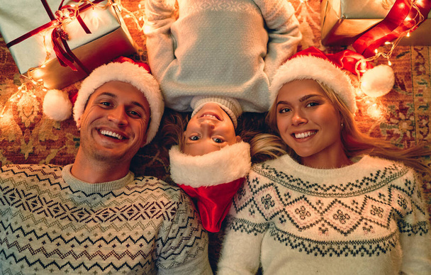 Merry Christmas and Happy New Year! Top view of happy family is lying on the floor with gift boxes and - Фото, изображение