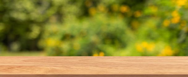 Pusty drewniany stół odizolowany na zielonym i żółtym tle natury bokeh. Do umieszczenia produktu lub montażu z naciskiem na blat stołu na pierwszym planie - Zdjęcie, obraz