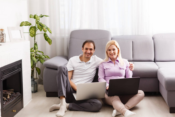 Happy young casual couple sitting working together at home office, smiling. - Foto, afbeelding