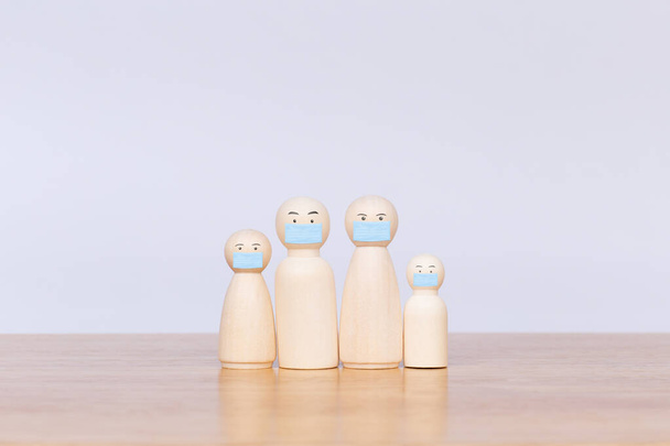 Wooden figurines representing family wearing a surgical mask protection of virus. Concept of protection corona virus or covid-19 - Foto, afbeelding