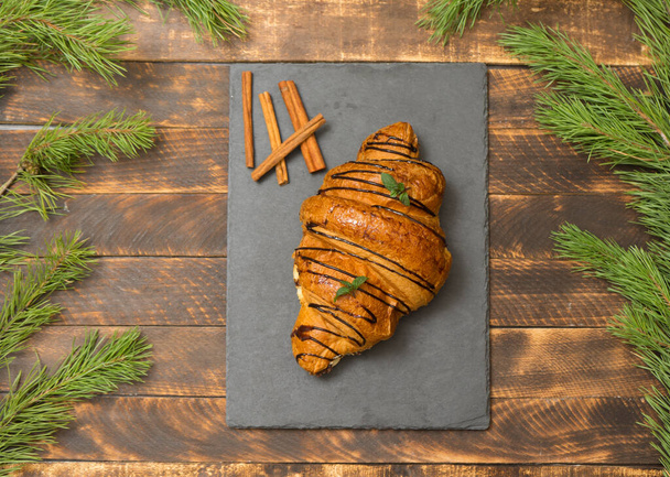 bun close-up on wooden rustic background. Croissant for new year - Photo, image