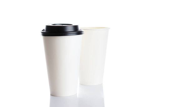 Белая бумажная чашка для горячего кофе с черной крышкой изолированы на белом фоне. Вынос пустой небольшой чайный стаканчик для оформления текста или баннера бренда - Фото, изображение