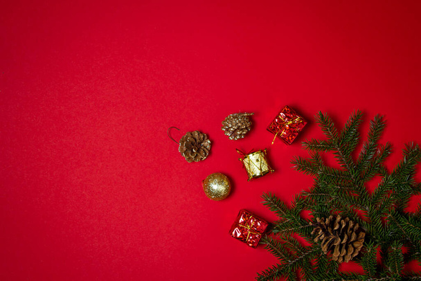 Ветки елки с рождественскими украшениями на красном фоне. Рождественский фон Новогодняя концепция. Есть место для надписи или логотипа - Фото, изображение