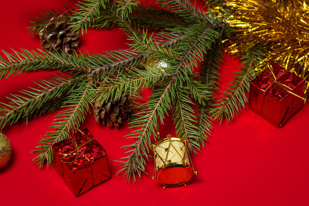 Χριστουγεννιάτικα κλαδιά δέντρου με χριστουγεννιάτικες διακοσμήσεις σε κόκκινο φόντο. Χριστουγεννιάτικο φόντο. Έννοια νέου έτους. - Φωτογραφία, εικόνα