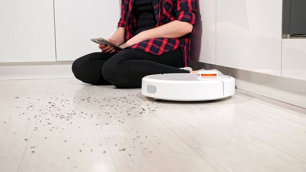 Nainen älypuhelin ohjaa robotti pölynimuri kotona - Valokuva, kuva