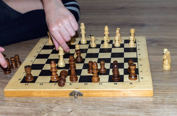 Les mains d'un garçon caucasien inconnu qui joue aux échecs sur un plancher de bois. Gros plan. - Photo, image