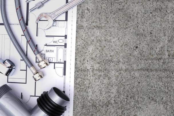 Top view of plumbing equipment and a blueprint project on a concrete floor background with copy space - Photo, Image