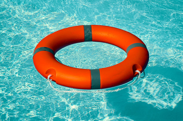 Boya salvavidas roja anillo de la piscina flotar en agua azul. Anillo de vida flotando sobre agua azul soleada. Anillo de vida en piscina - Foto, Imagen