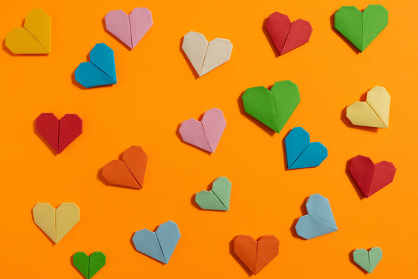 Καρδιές Origami φτιαγμένες με χρωματιστό χαρτί για συγχαρητήρια για την ημέρα του Αγίου Βαλεντίνου για τα ερωτευμένα ζευγάρια, σε κίτρινο φόντο. Έννοια αγάπης - Φωτογραφία, εικόνα
