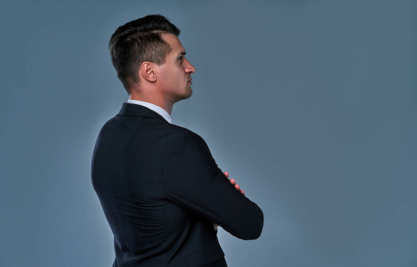Obrázek pohledného seriózního muže v černobílém obleku, jak stojí nad šedým pozadím a dívá se stranou. - Fotografie, Obrázek