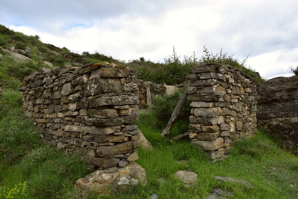 Старый сухой каменный загон, разрушенный течением времени на вершине горы. Приют для животных и пастухов, защищенный от северного ветра. - Фото, изображение