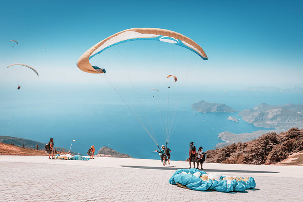 09 September 2020, Babadag, Oludeniz, Turkey: Many paragliding adventurers takeoff in tandem with instructor after a short training session for recreational flight and descent to the sea - 写真・画像