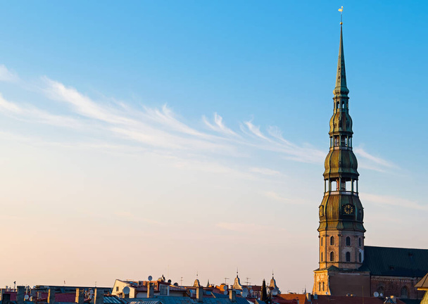 Symbool van Riga, oude klok op middeleeuwse kerktoren tussen daken oude gebouwen met Europese architectuur - Foto, afbeelding